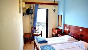 A hotel room with two beds, a desk, a chair, a television, and a balcony. - Blue bay Hotel (Karpathos)