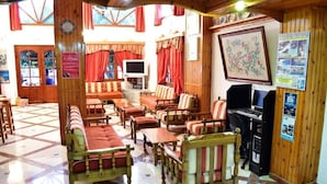 A cozy, well-lit room with wooden furniture, a television, and a computer. - Blue bay Hotel (Karpathos)