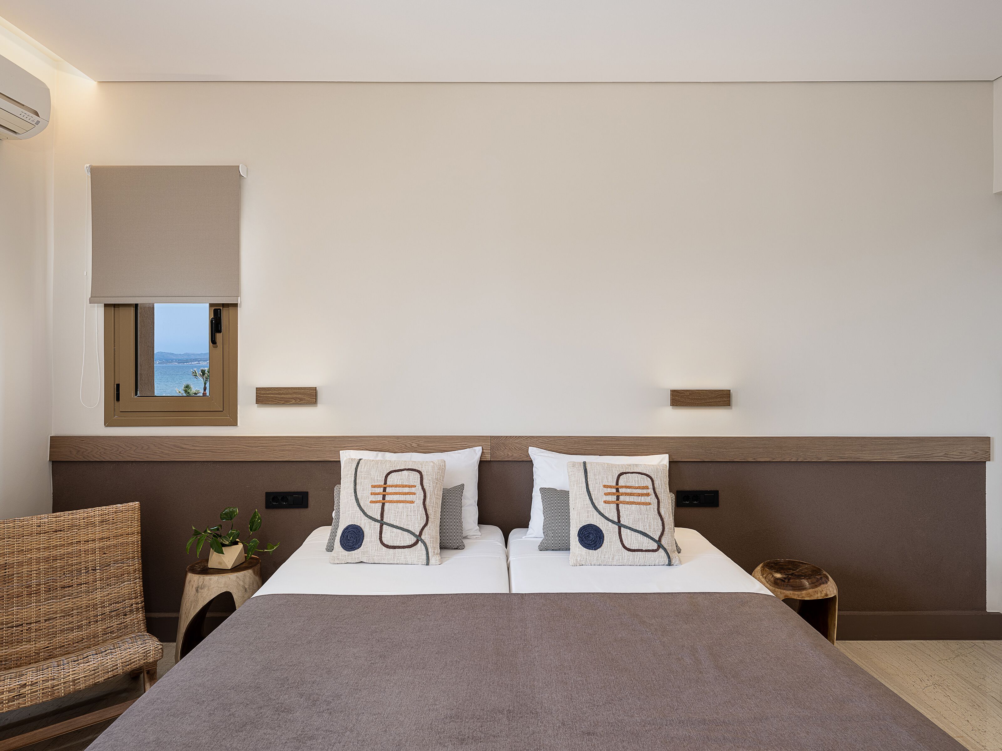 A bedroom with a bed, two pillows, a bedside table, a chair, and a window with a view.