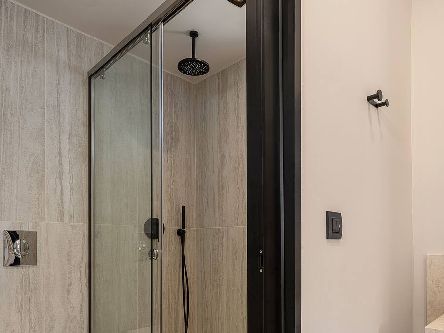 Un bany modern amb dutxa de vidre, vàter blanc i un envàs de fusta.