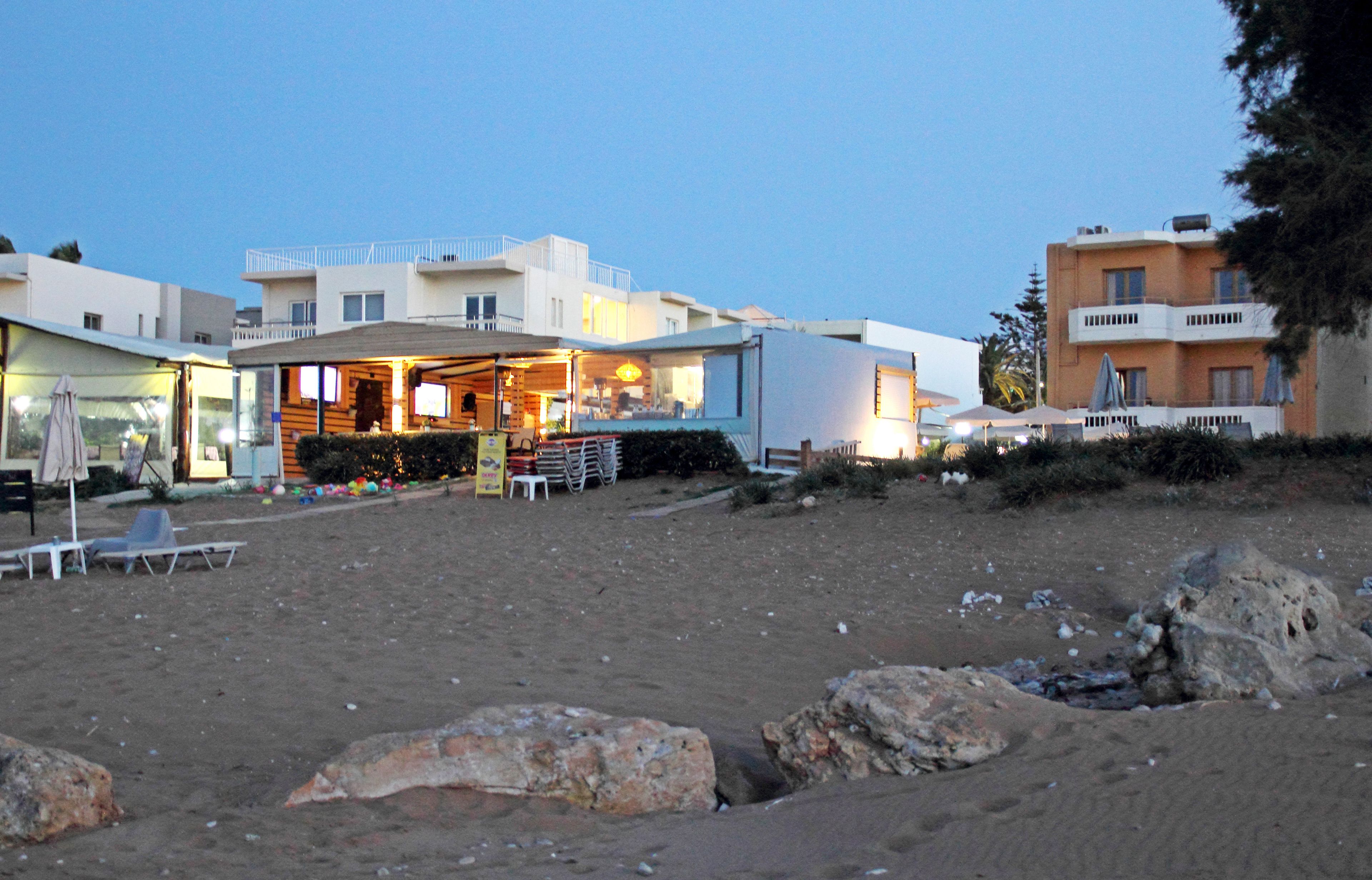 A beachfront property with a bar area, outdoor seating, and a sandy beach.
