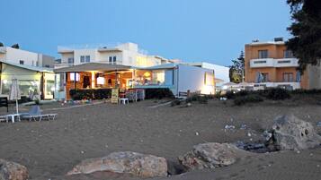 A beachfront property with a bar area, outdoor seating, and a sandy beach.