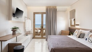 Une chambre d’hôtel moderne équipée d’un lit, d’une table de chevet, d’une télévision et offrant une vue sur la mer grâce à une porte vitrée.