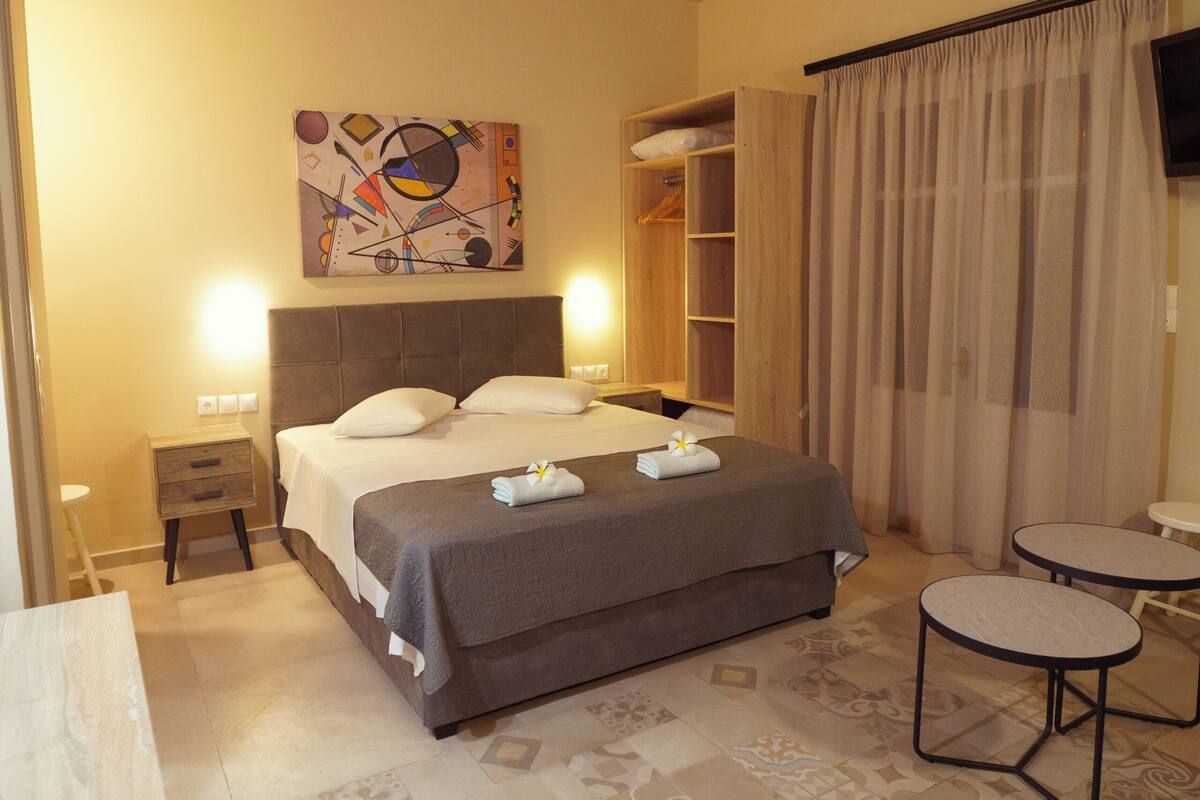 A bedroom with a bed, bedside tables, a wardrobe, a small table, and a TV.