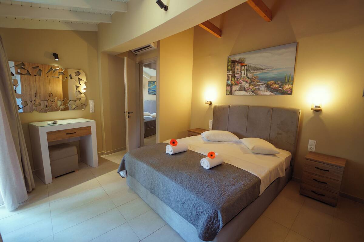 A bedroom with a bed, bedside tables, a desk, and a painting on the wall.