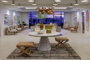 Un salon moderne avec une table de salle à manger ronde, des meubles en osier et une grande fenêtre donnant sur la ville.