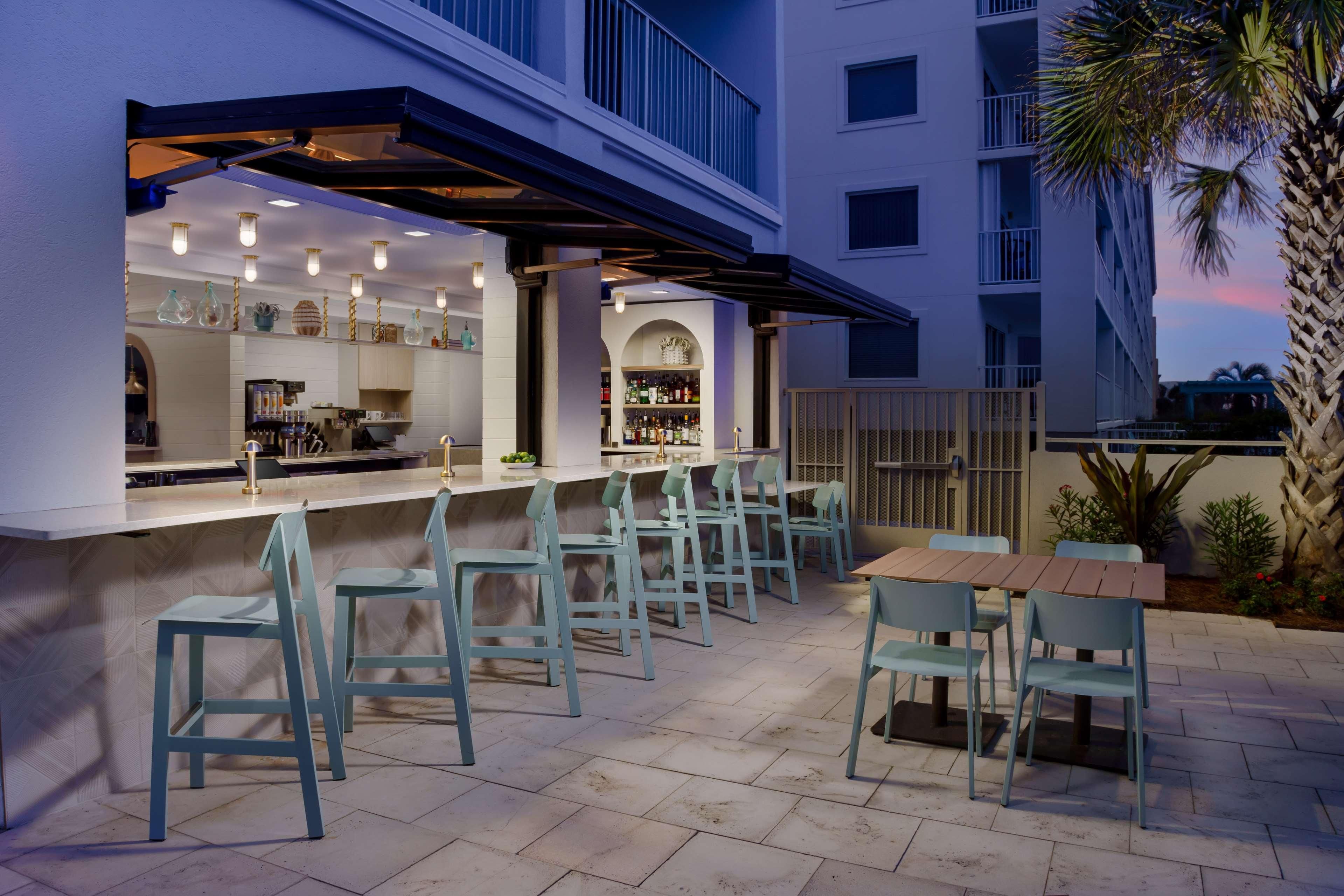 An outdoor bar area with a counter, multiple chairs, and a table.