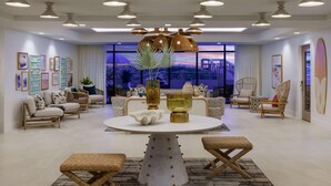 Uma sala de estar moderna com uma mesa de jantar redonda, móveis de vime e uma janela grande com vista para a cidade.