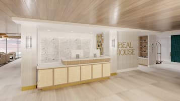 A modern hotel lobby with a reception desk, a seating area with sofas, and a view of the outdoors.