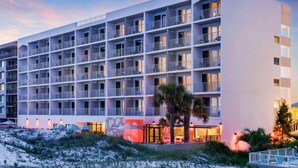 Un hôtel à plusieurs étages doté de balcons, offrant une vue sur la plage et comprenant des espaces de détente en plein air.