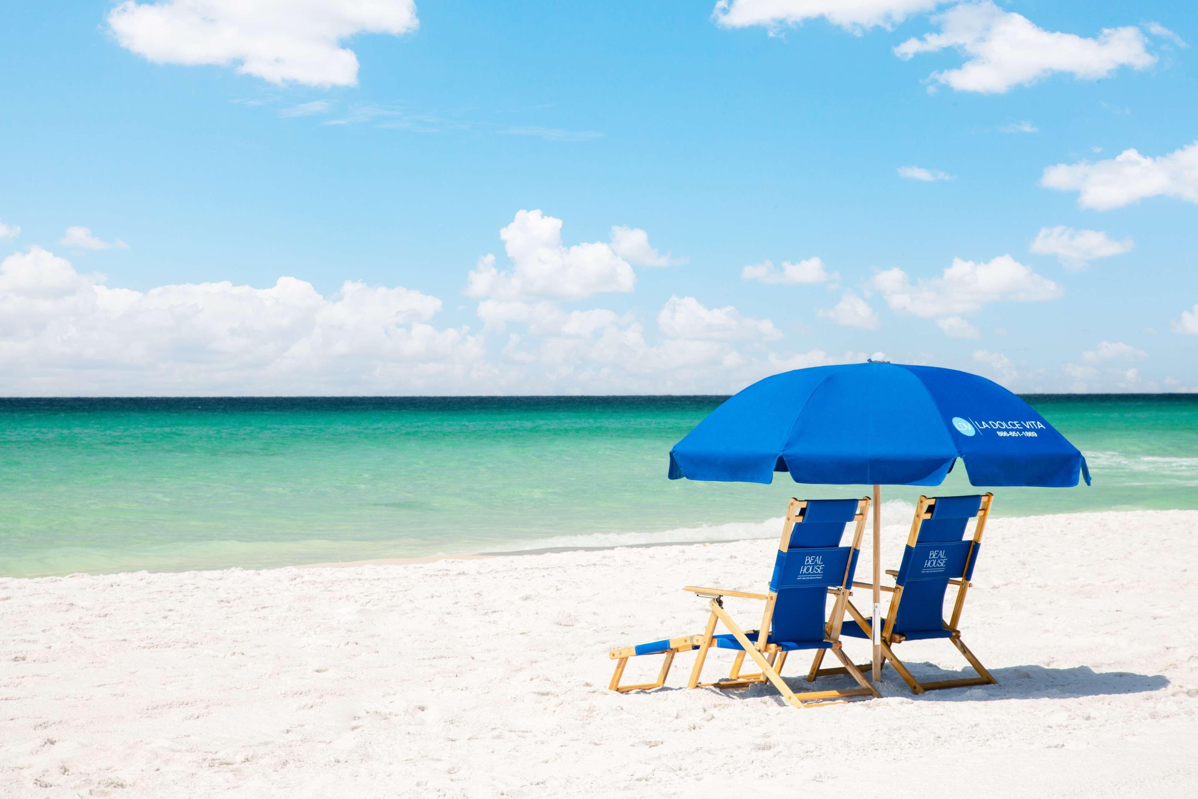 A beach scene with a blue umbrella and two blue lounge chairs with "La Dolce Casa" branding.