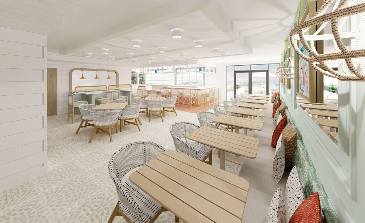 A spacious, well-lit indoor area with multiple seating arrangements, including tables and wicker chairs, and a large window providing a view of the outdoors.