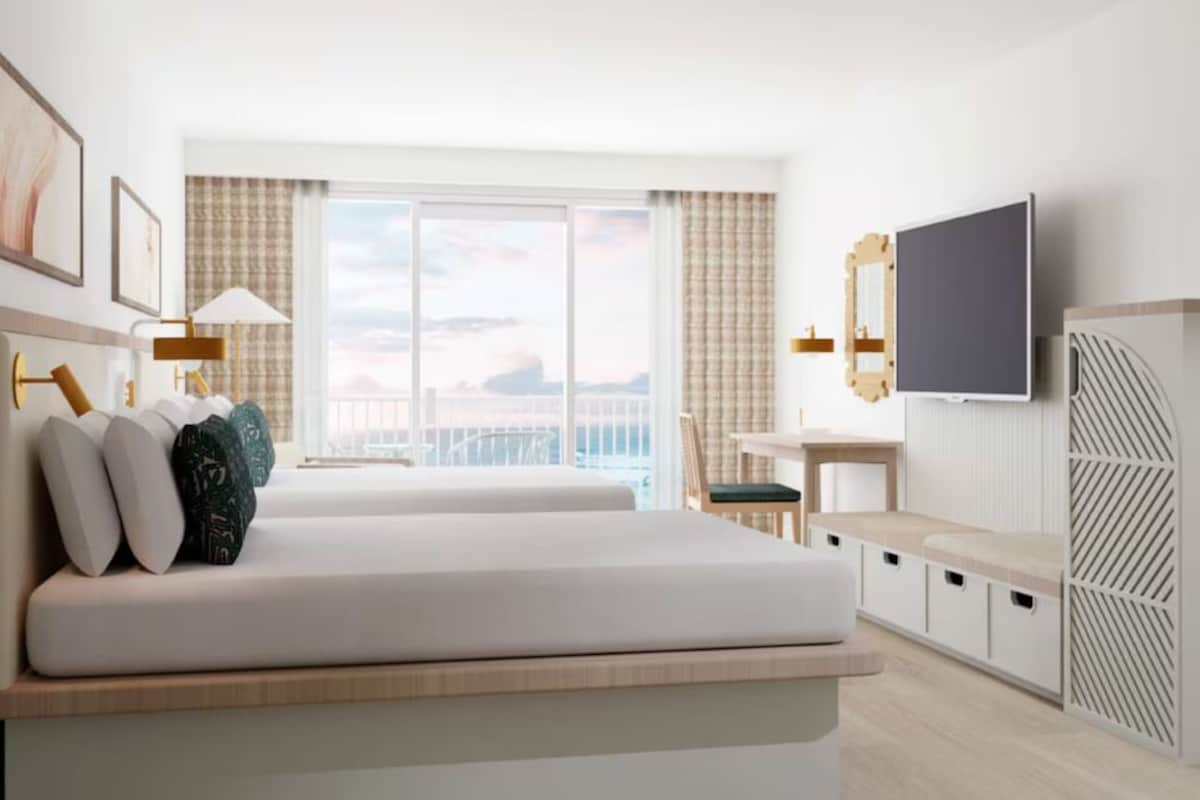 Una camera d'hotel moderna con un letto grande, una scrivania, una televisione e un balcone con vista.