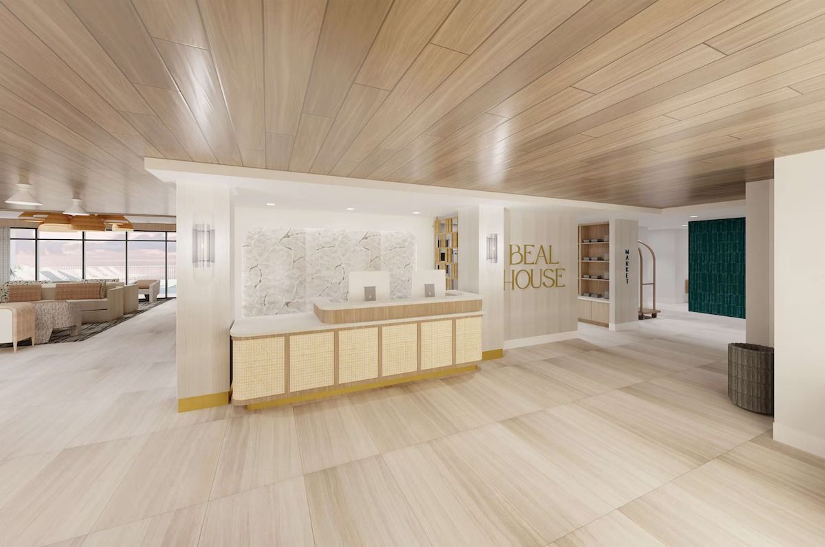 A spacious lobby with a reception desk, wooden flooring, and a view of the outdoors.