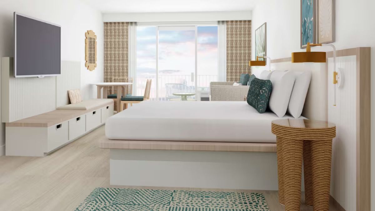 Quarto de hotel moderno com uma cama grande, televisão, escrivaninha e varanda com vista.