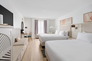 A hotel room with two beds, a desk, a chair, and a small seating area.