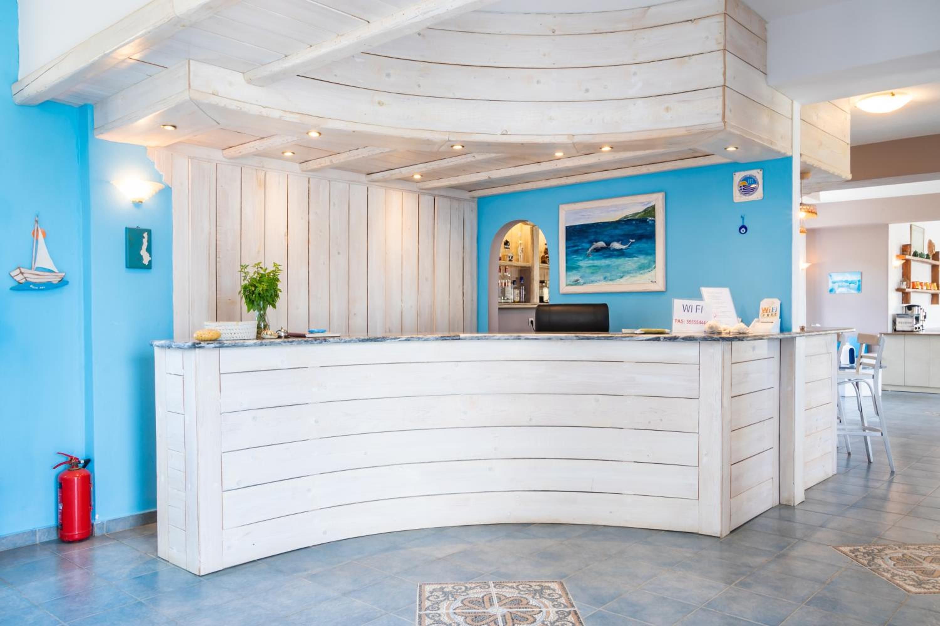 Un comptoir d’accueil au design incurvé, un mur bleu orné de motifs évoquant le thème maritime et un sol carrelé.