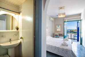 A hotel room with a bathroom, a bed with a view, and a balcony.