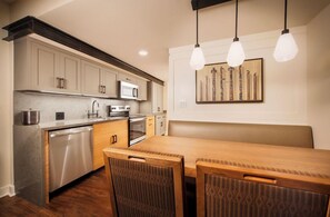 Une cuisine moderne dotée d’appareils électroménagers en acier inoxydable, de meubles en bois et d’un coin repas avec une table et des chaises en bois.