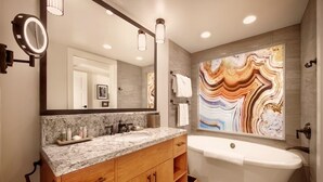 A modern bathroom with a freestanding bathtub, a marble countertop vanity, and a large mirror with integrated lighting. - Copper Creek Villas and Cabins at Disneys Wilderness Lodge (Lake Buena Vista)