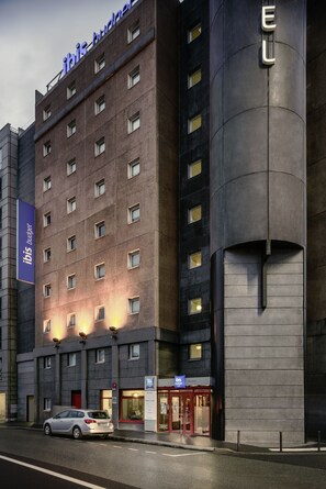 Un hôtel doté d’une façade moderne, de nombreuses fenêtres et d’une entrée imposante avec une porte rouge.