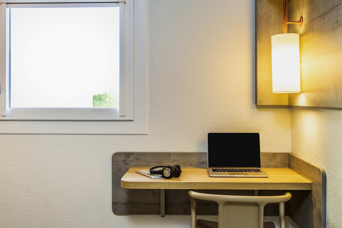 Un espace de travail avec un ordinateur portable, un appareil photo et un carnet sur un bureau en bois.