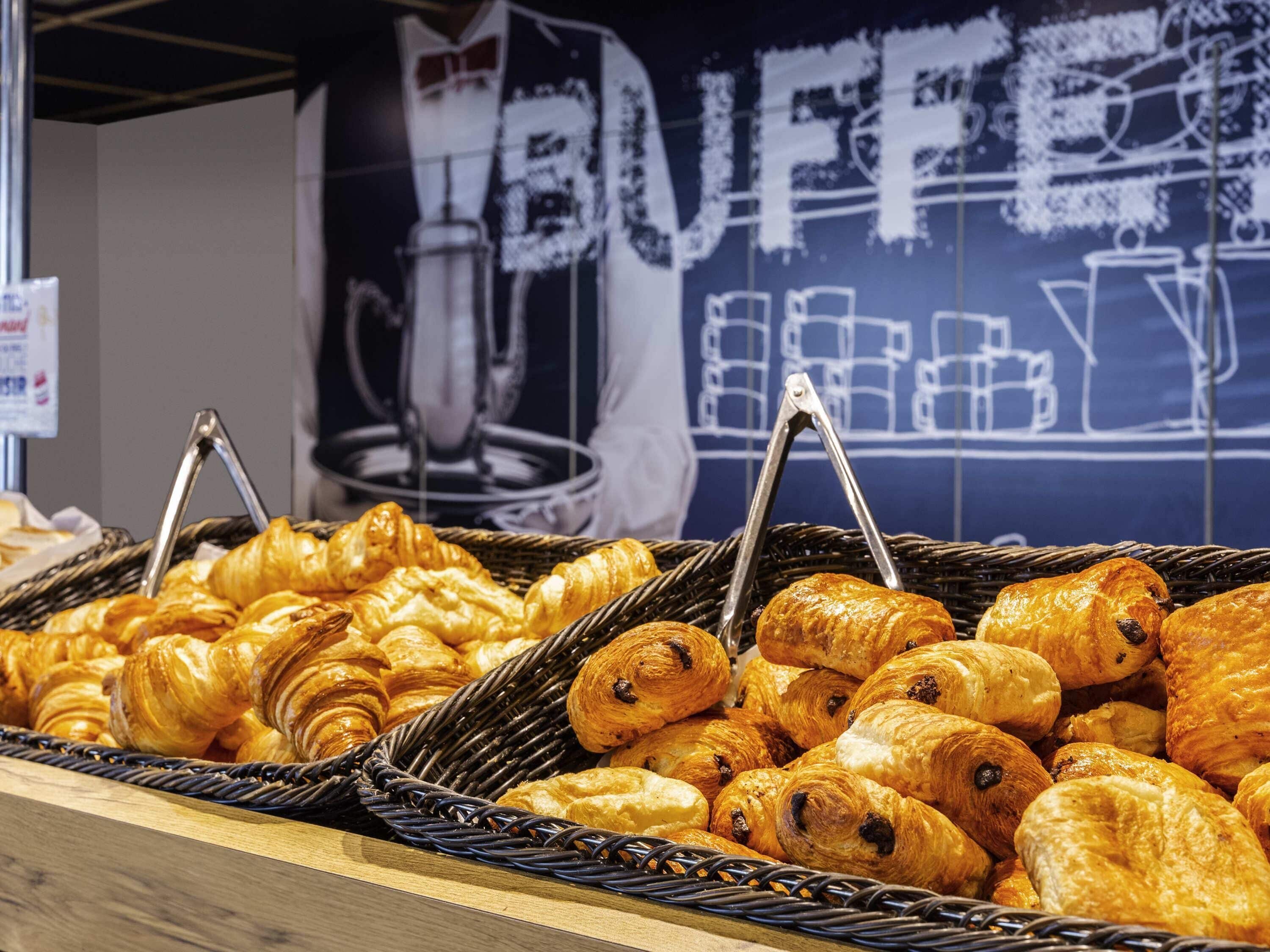 Une variété de pâtisseries présentées dans des paniers, avec une pancarte indiquant « BUFFET » en arrière-plan.