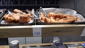 A bakery display with baskets of bread and croissants, a chalkboard menu, and a sign indicating daily baked goods. - ibis budget Paris Porte d'Italie Est (Le Kremlin-Bicetre)