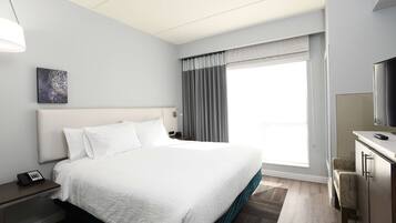 Una habitación de hotel con una cama grande, un escritorio con televisor y una ventana con cortinas.