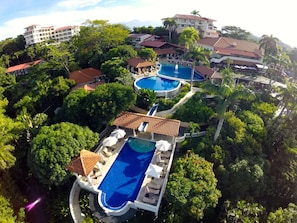 A resort with multiple swimming pools surrounded by lush greenery and palm trees.