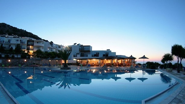 A swimming pool with lounge chairs and a building with multiple floors and balconies. - Semiramis Village (Hersonissos)