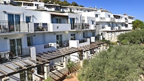 A row of white buildings with balconies, a wooden pergola, and a hillside in the background. - Semiramis Village (Hersonissos)