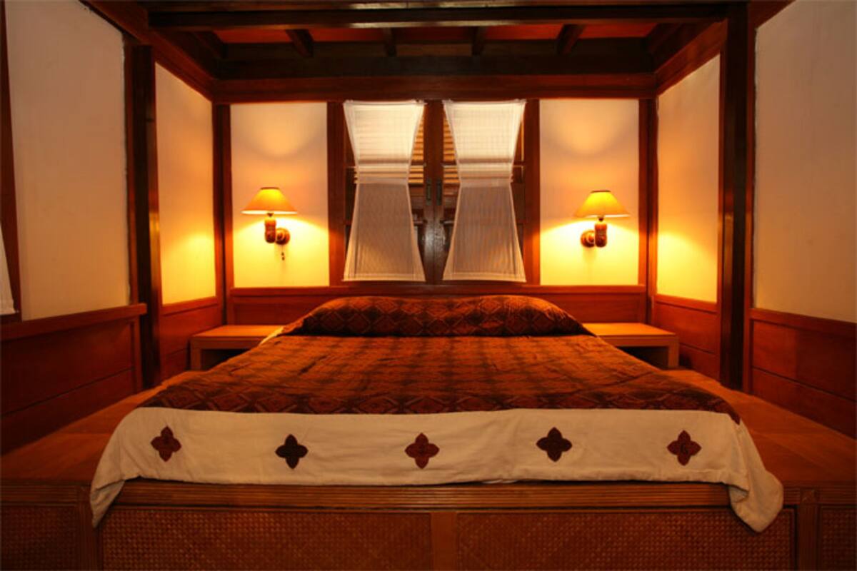 Habitació d'hotel amb un llit gran, dues taules de nit i dues làmpades penjades a la paret.