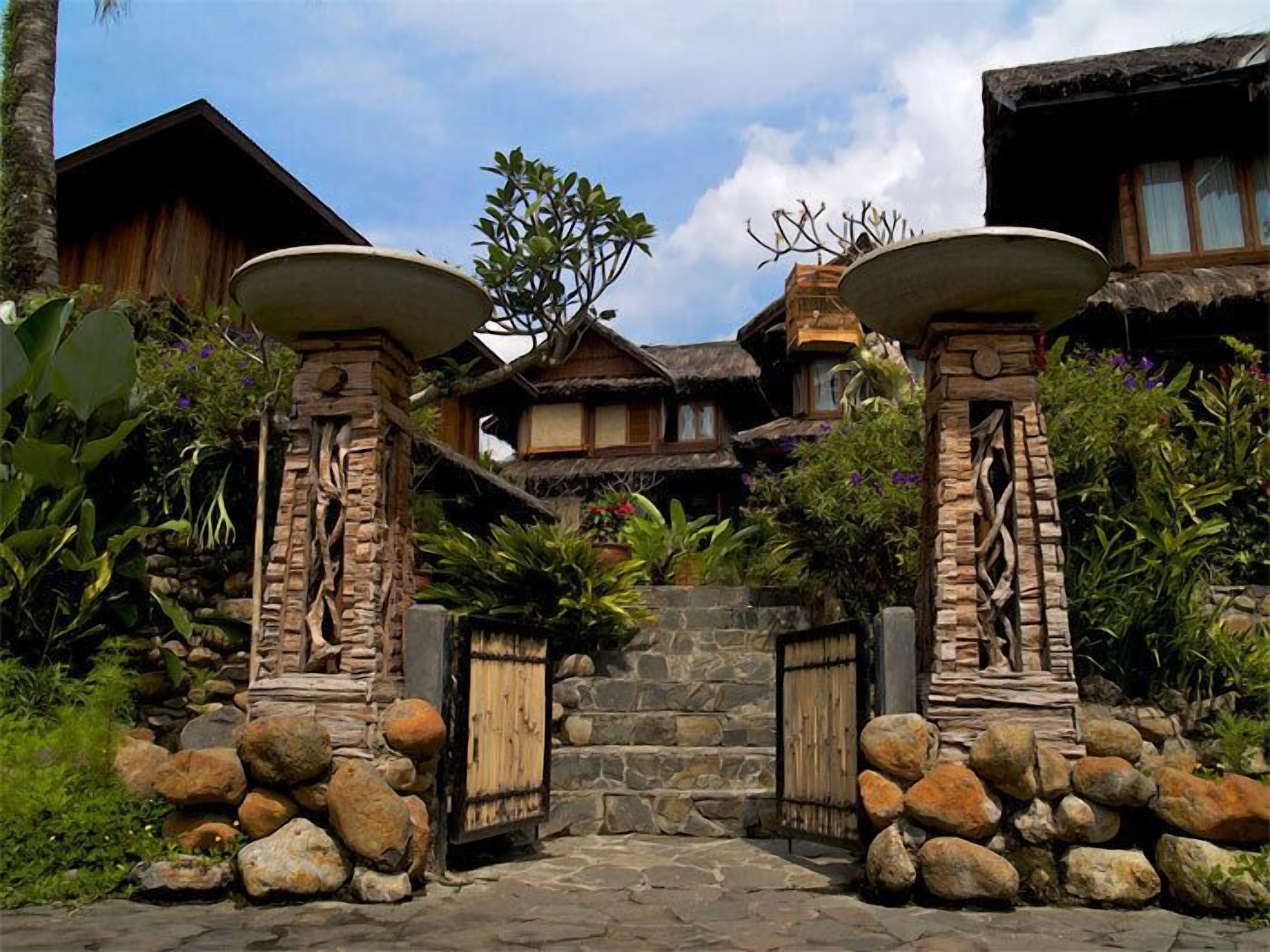 Un edificio de estilo tradicional con entrada de piedra, puertas de madera y tejado de paja.