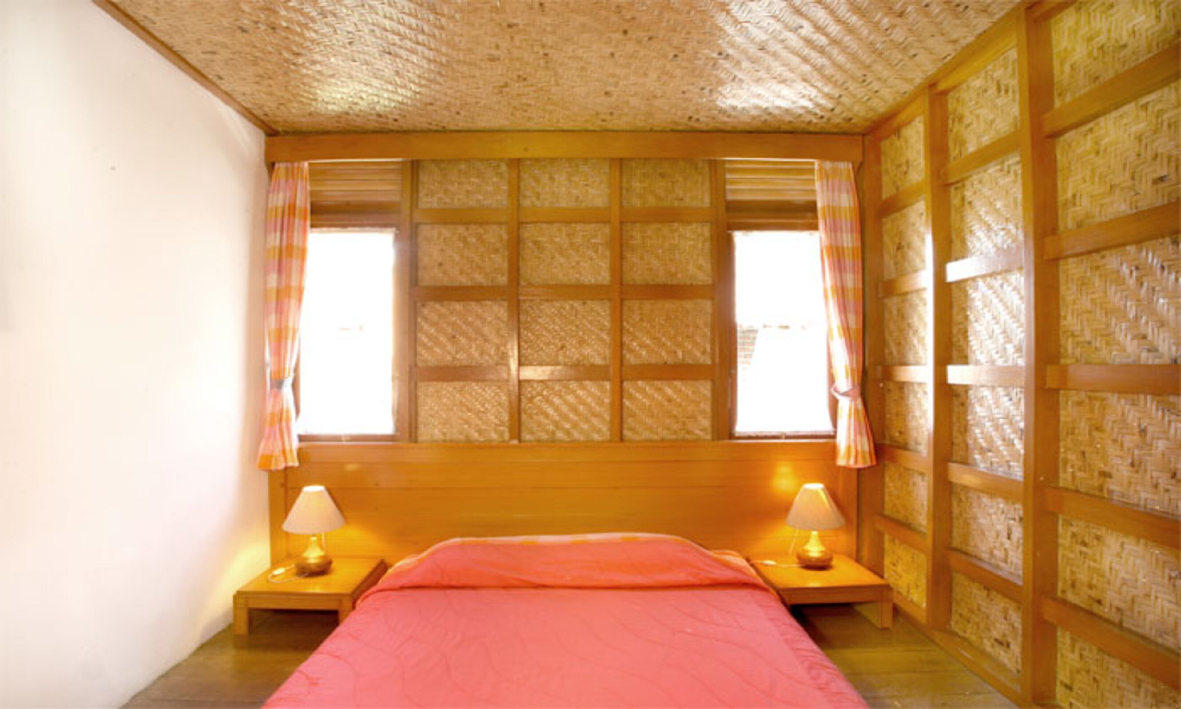 Una habitación con cama, dos mesitas de noche y una ventana con cortinas.