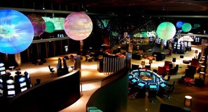 Un interior moderno con máquinas de juego, zonas de estar y esferas grandes iluminadas.