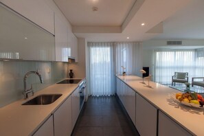 A modern kitchen with a central island, stainless steel appliances, and a dining area with a view.