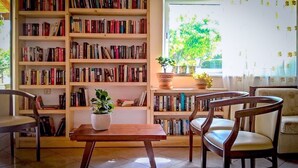 A cozy reading room with a large bookshelf, a wooden table, and two chairs. - Villa Vicky (Hersonissos)