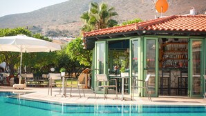 A poolside bar with outdoor seating and a mountain backdrop. - Villa Vicky (Hersonissos)