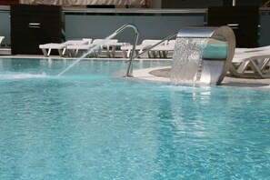 Une piscine agrémentée d’un élément décoratif aquatique, de chaises longues et dotée d’une architecture moderne.