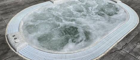 A hot tub with a textured edge and a tiled floor surrounding it.
