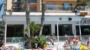 A multi-story hotel with a pool area in front, featuring a clear sky and palm trees. - Reymar Playa (Malgrat de Mar)