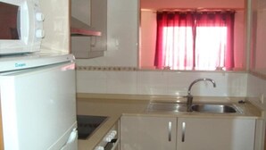 A compact kitchen with a microwave, sink, and cabinets. - Pompeya (Peniscola)