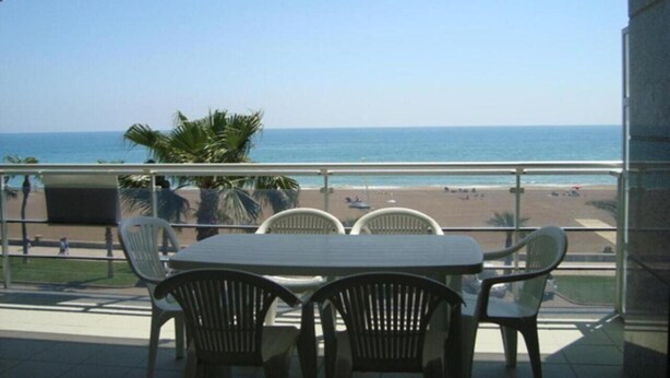 A balcony with a table and chairs, overlooking a beach and the ocean. - Pompeya (Peniscola)