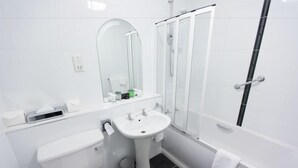 Une salle de bain moderne équipée de toilettes, d’un lavabo, d’un miroir et d’une douche.