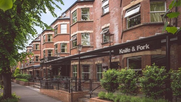 Une rangée de maisons de ville en briques, avec un restaurant appelé « Knife & Fork » situé au rez-de-chaussée.