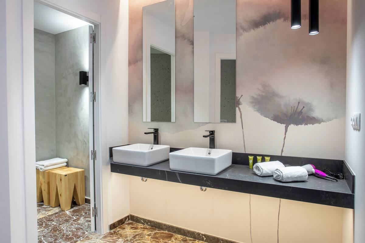 A modern bathroom with two sinks, a large mirror, and a towel rack.