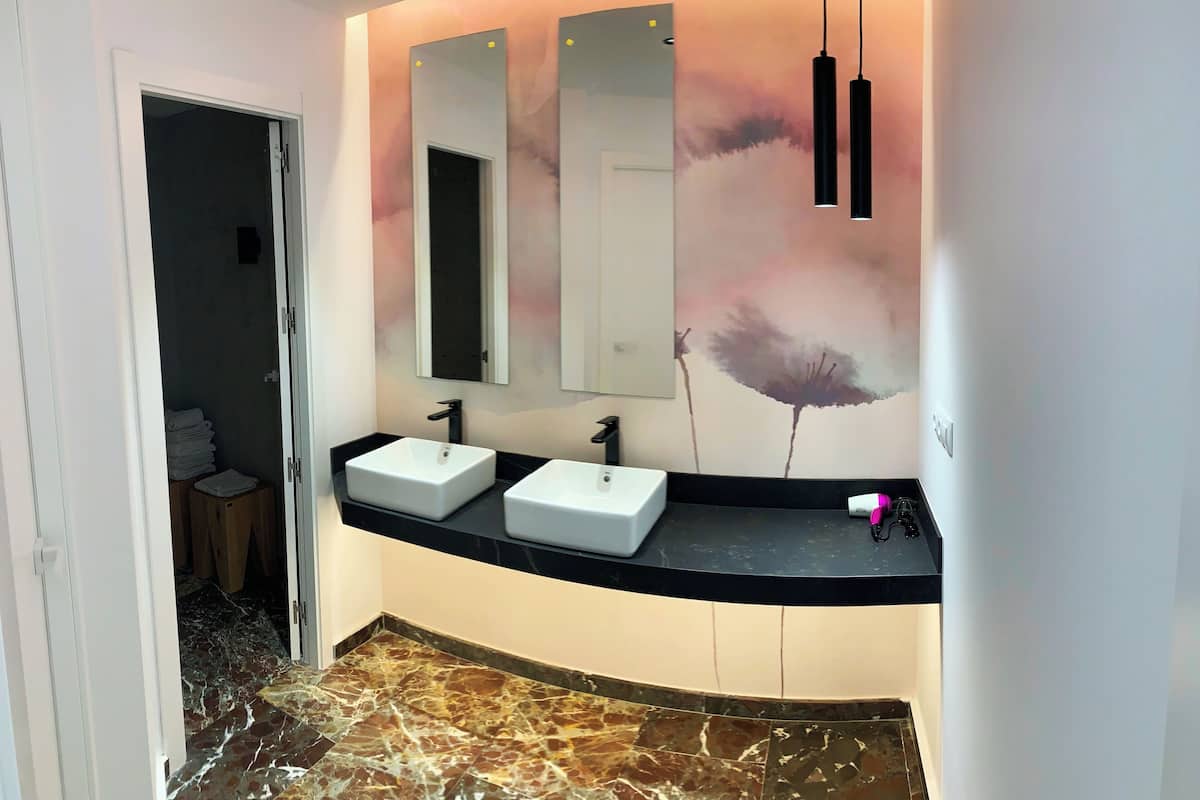 A modern bathroom with two sinks, a large mirror, and a marble floor.