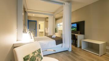 Una habitación de hotel moderna con una cama grande, televisor, escritorio y zona de ducha.