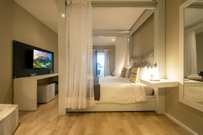 A modern bedroom with a bed, bedside table, TV, and a view of a mountain landscape. - Pousada Aroma do Mar (Búzios)